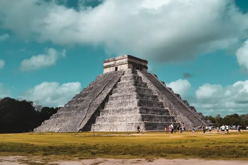 Family with children exploring Chichen Itza ruins, kids wearing sun hats looking at El Castillo pyramid