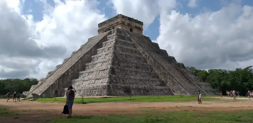 Side view of El Castillo pyramid at Chichen Itza with dramatic clouds